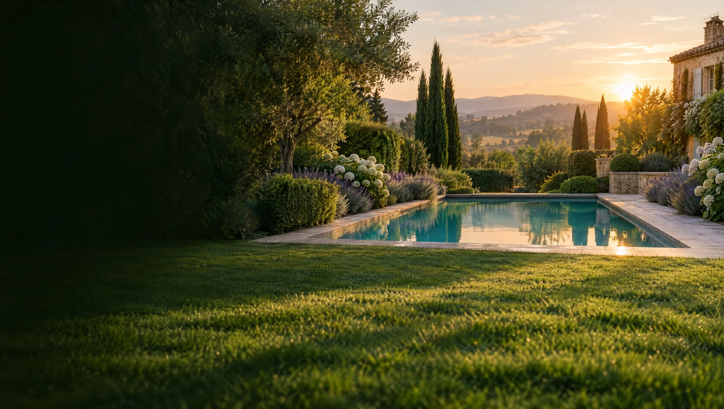 Jardin privé avec pelouse parfaitement tondue et piscine turquoise, en fin de journée