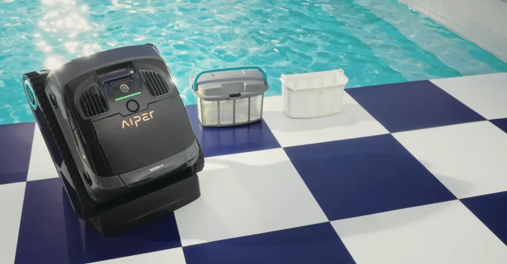 Aiper Scuba X1 posé au bord d'une piscine avec ses deux paniers filtrants, prêt à être mis à l'eau
