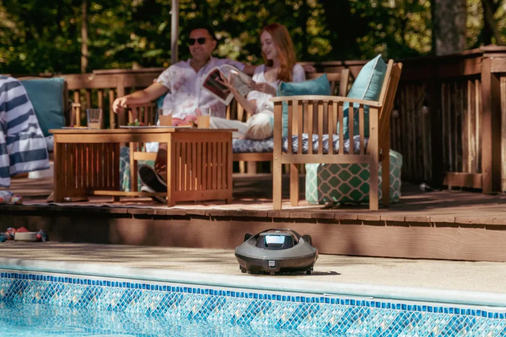 Aiper Seagull SE vu de face au bord d'une piscine, hublot avant turquoise apparent