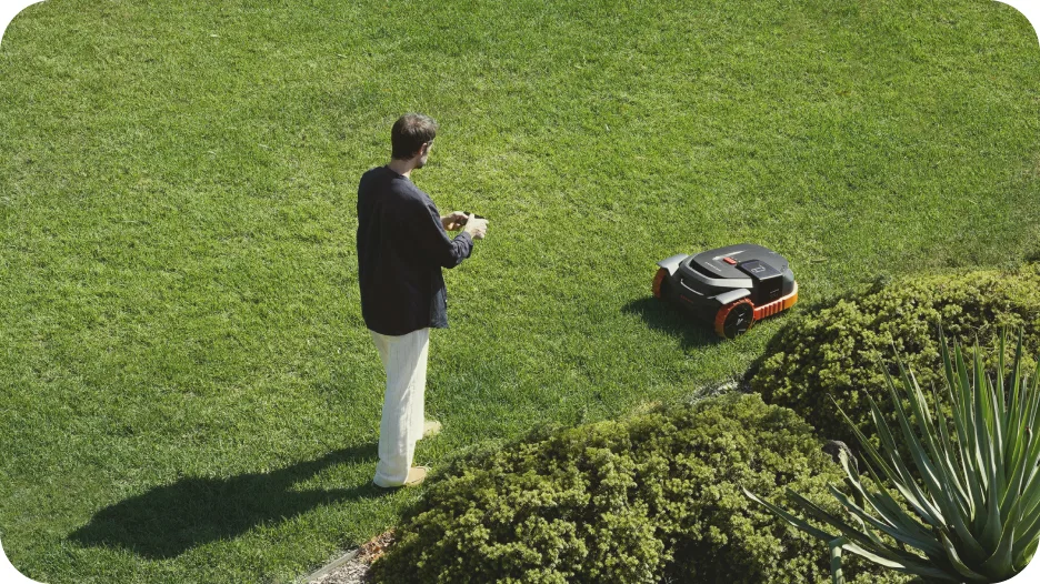 Utilisateur pilotant la cartographie de son robot tondeuse Segway Navimow X3 depuis son smartphone dans le jardin